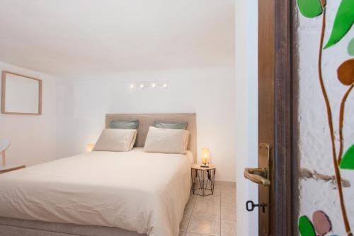 - une chambre dotée d'un lit blanc avec une bougie sur une table dans l'établissement OLIVIERS -Agréable 2 pièces dans maison bourgeoise, à Menton