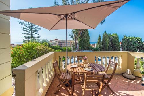 une terrasse avec une table et des chaises sous un parasol dans l'établissement OLIVIERS -Agréable 2 pièces dans maison bourgeoise, à Menton