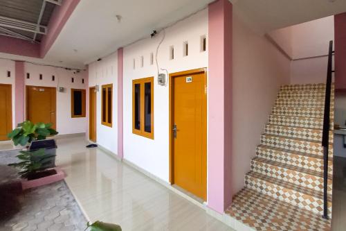 a hallway of a school with yellow doors and stairs at RedDoorz Syariah near JBC Jambi in Jambi