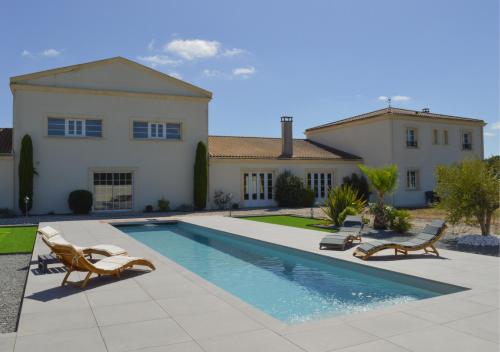 une maison avec une piscine devant une maison dans l'établissement La Tour Bornéo du Château Saint-Laurent, à Saint-Laurent-de-Médoc