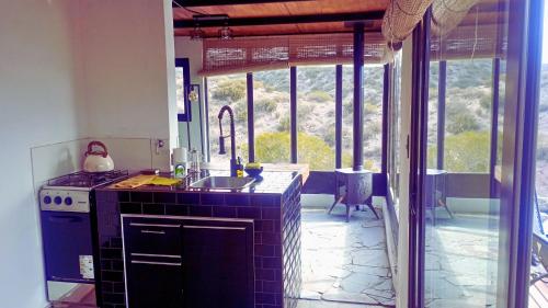 a kitchen with a stove and a sink and a window at RevolucionArte Potrerillos in Ciudad Lujan de Cuyo
