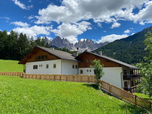 a house in a field with mountains in the background at MiraOdle Apartments in Villnoss