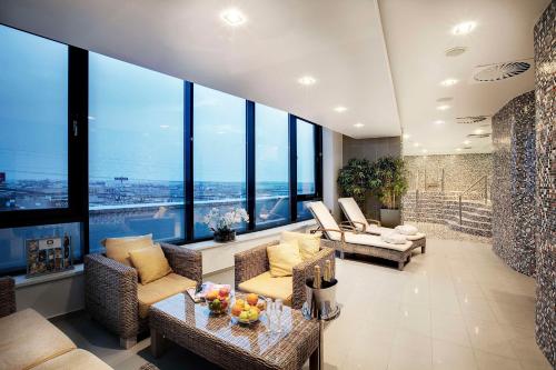 a living room with couches and chairs and large windows at NH Bratislava Gate One in Bratislava