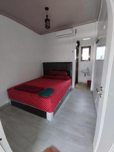 una camera con letto rosso e un bagno di Krui NFs hotel a Krui