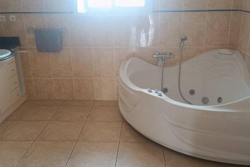 a bath tub in a bathroom with a tiled floor at Maison au calme, proche plage in Labenne