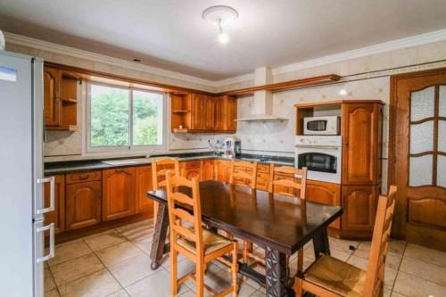 une cuisine avec des armoires en bois et une table avec des chaises dans l'établissement Maison au calme, proche plage, à Tarnos