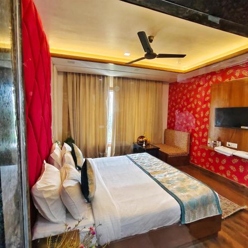 a bedroom with a large bed with a red wall at Rich Grand Hotel in Agra