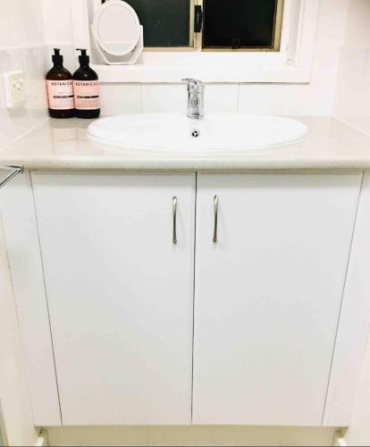 a white bathroom vanity with a sink and a mirror at Sunny Shackell - Echuca Moama Holiday Accommodation in Echuca
