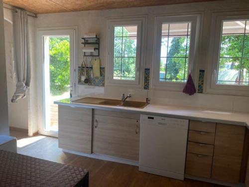 une cuisine avec un évier et deux fenêtres dans l'établissement Vaste appartement, jardin, proximité océan, à Capbreton