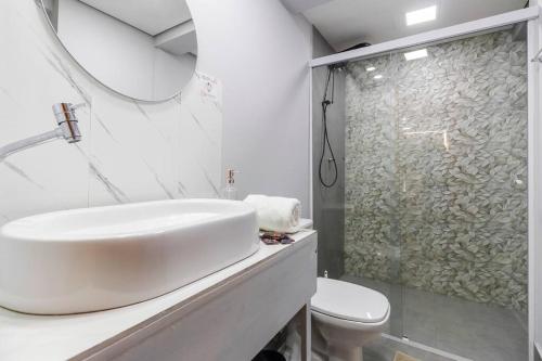 a white bathroom with a sink and a shower at Aconchego em sampa in Sao Paulo