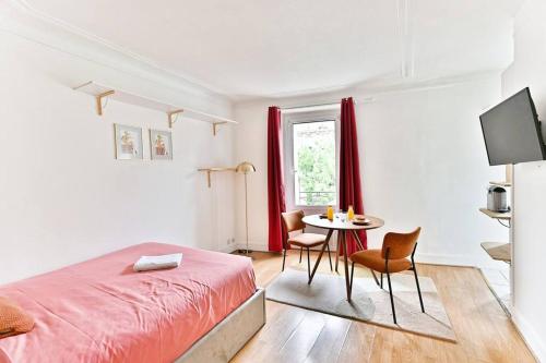 une chambre avec un lit et une table avec des chaises dans l'établissement Petit Studio Paris Voltaire Nation, à Paris