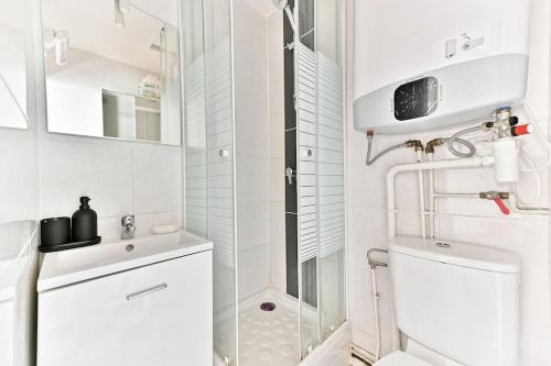 une salle de bain blanche avec douche et toilettes dans l'établissement Petit Studio Paris Voltaire Nation, à Paris