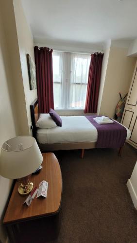 a bedroom with two beds and a table with a lamp at Heathlands Hotel in Bournemouth