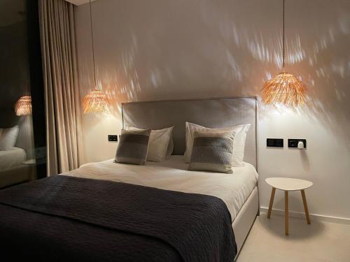 a bedroom with a bed with two pillows and a table at Exclusive Beach House with full sea view, Luxury and Comfort by the Sea in Murtinheira