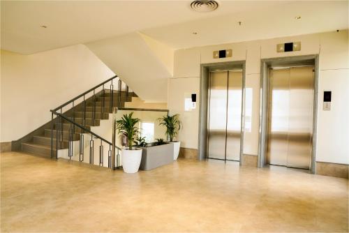 an empty lobby with stairs and potted plants at The Grand Sona in Deoghar