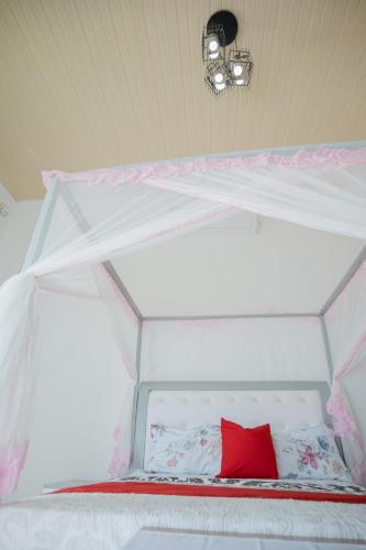 a white canopy bed with a red pillow on it at The city Block Apartment in Bujumbura