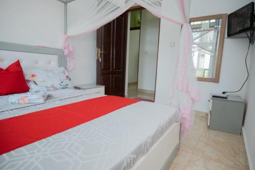 a bedroom with a bed with a red and white comforter at The city Block Apartment in Bujumbura