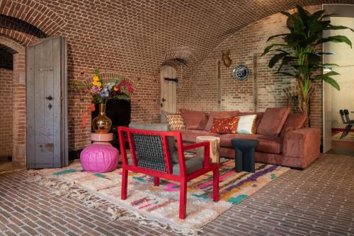 a living room with a couch and a red chair at Fort Vuren in Vuren