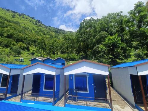a row of blue houses with a mountain in the background at Lake Haven Resort, Sari, Chopta in Sari