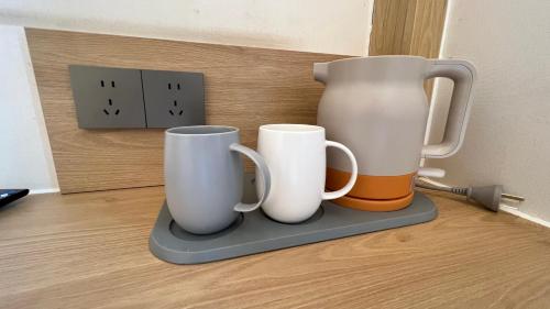 three coffee mugs and a jug on a shelf at 嵩山居-丽晶精品民宿 in Dengfeng