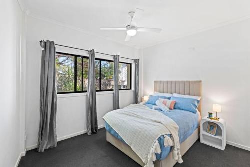 a white bedroom with a bed and a window at modern apartment in the heart of Norman Park in Brisbane