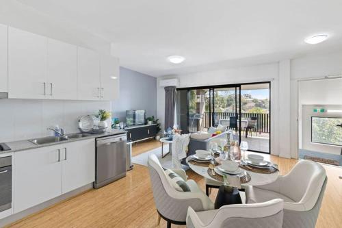 a kitchen and living room with a table and chairs at modern apartment in the heart of Norman Park in Brisbane