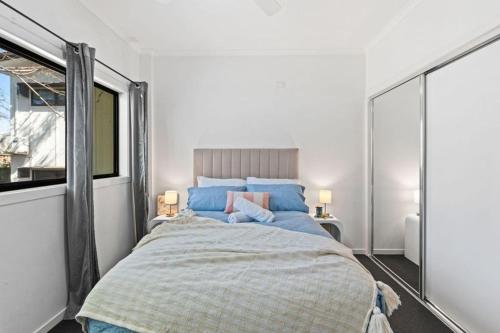 a bedroom with a large bed with blue pillows at modern apartment in the heart of Norman Park in Brisbane