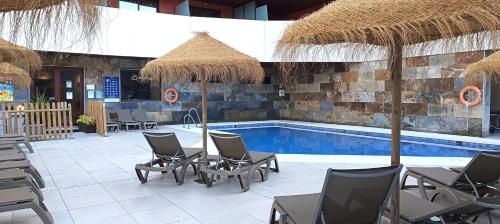 a swimming pool with chairs and a swimming pool at Ohtels Campo De Gibraltar in La Línea de la Concepción