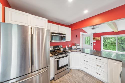 a kitchen with red walls and a stainless steel refrigerator at Charming Stowe Retreat with Mountain Views home in Stowe