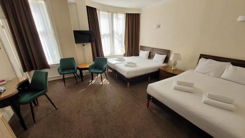 a hotel room with two beds and a table and chairs at Heathlands Hotel in Bournemouth