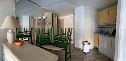 Il comprend un salon avec des chaises vertes et une cuisine. dans l'établissement Studio mezzanine golf St cyprien, à Saint-Cyprien