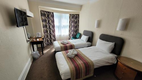 a hotel room with two beds and a television at Heathlands Hotel in Bournemouth