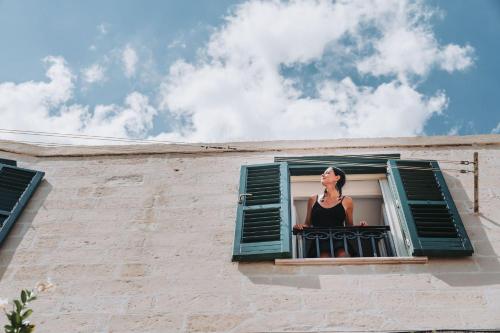 a woman in a black dress looking out of a window at La Casa di Ele in Matera