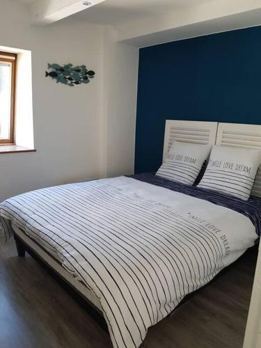 une chambre avec un grand lit avec un mur bleu dans l'établissement Loue appartement 50m de la plage 2 ch 4 ou 5 pers, à Pléneuf-Val-André