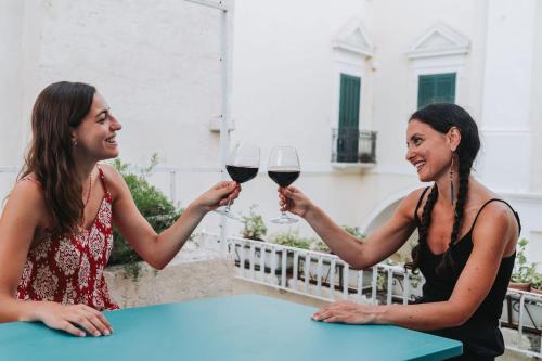 two women are holding glasses of red wine at La Casa di Ele in Matera