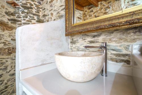 a stone sink in a bathroom with a mirror at RODIBLUE VILLAGE Apartments in Rodia