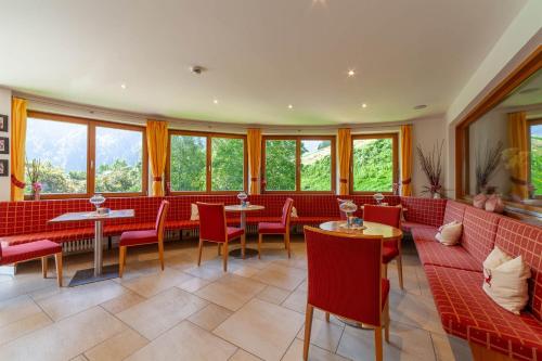 a restaurant with red couches and tables and windows at Hotel St. Pankraz in San Pancrazio dʼUltimo