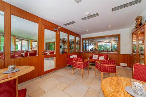 a restaurant with red chairs and tables and windows at Hotel St. Pankraz in San Pancrazio dʼUltimo