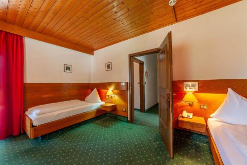 a room with two beds and a door to a bedroom at Hotel St. Pankraz in San Pancrazio dʼUltimo