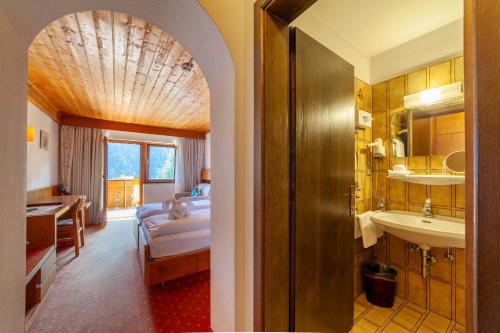 a bathroom with a bed and a sink in a room at Hotel St. Pankraz in San Pancrazio dʼUltimo