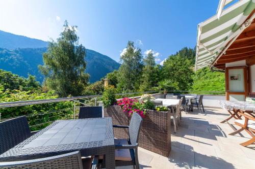 a patio with tables and chairs and mountains in the background at Hotel St. Pankraz in San Pancrazio dʼUltimo
