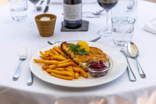 a plate of food with french fries and a bottle of wine at Hotel St. Pankraz in San Pancrazio dʼUltimo