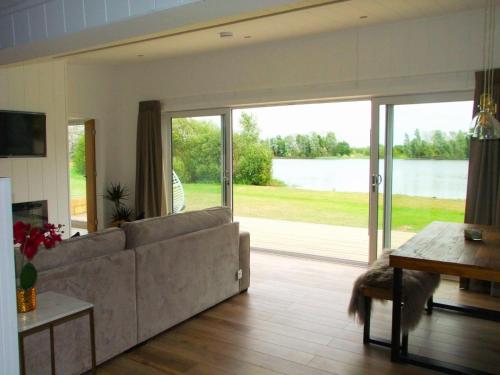 a living room with a couch and a large sliding glass door at Phoenix Lodge - Luxury 2 ensuite bedrooms, lakeside views in Newark upon Trent