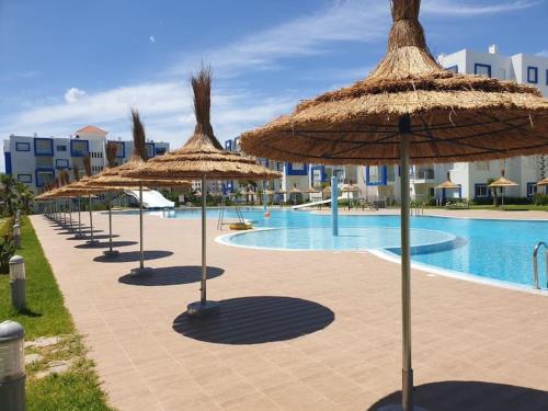 カボ・ネグロにあるcomplexe avec piscineのプールの横に並んだ藁傘