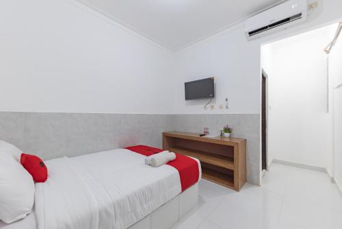 a white bedroom with a bed and a television at RedDoorz at Kedawung Aurel Cirebon in Plered
