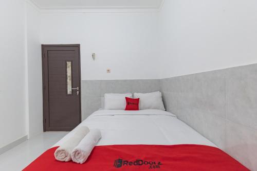 a bedroom with a white bed with a red pillow at RedDoorz at Kedawung Aurel Cirebon in Plered