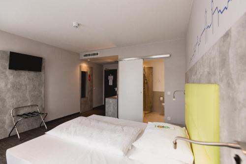 a bedroom with a white bed and a yellow chair at SleepySleepy Hotel Dillingen in Dillingen an der Donau