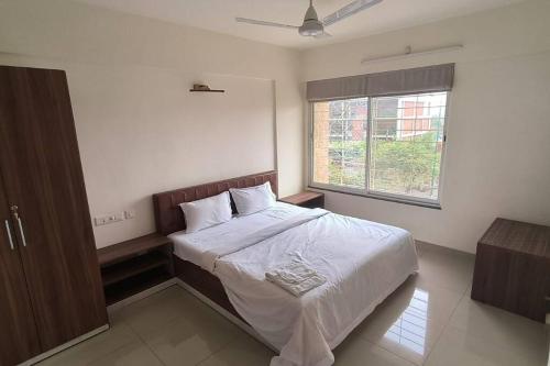 a bedroom with a large bed with white sheets and a window at Mihan Home Stay in Nagpur