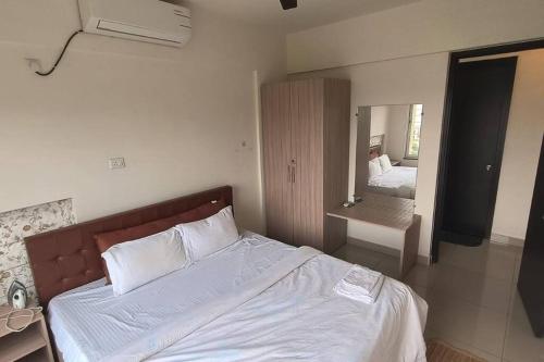 a bedroom with a bed with white sheets and a mirror at Mihan Home Stay in Nagpur