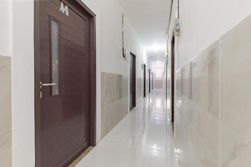 a hallway with a brown door and white walls at RedDoorz at Kedawung Aurel Cirebon in Plered